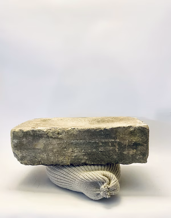 Soft sculpture head crushed by a brick