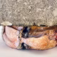 Soft sculpture head crushed by a brick