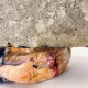 Soft sculpture head crushed by a brick