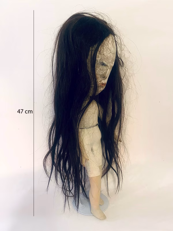 Uncanny girl doll with long dark brown hair.