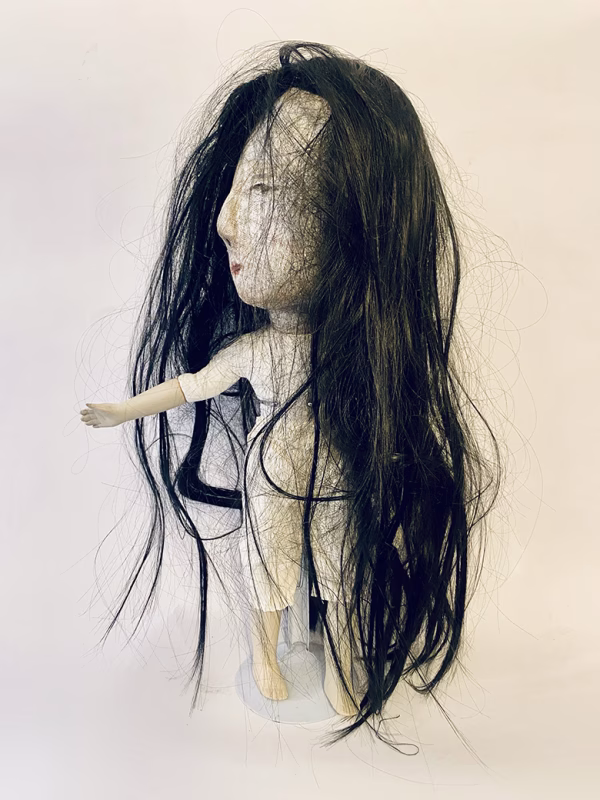 Uncanny girl doll with long dark brown hair.