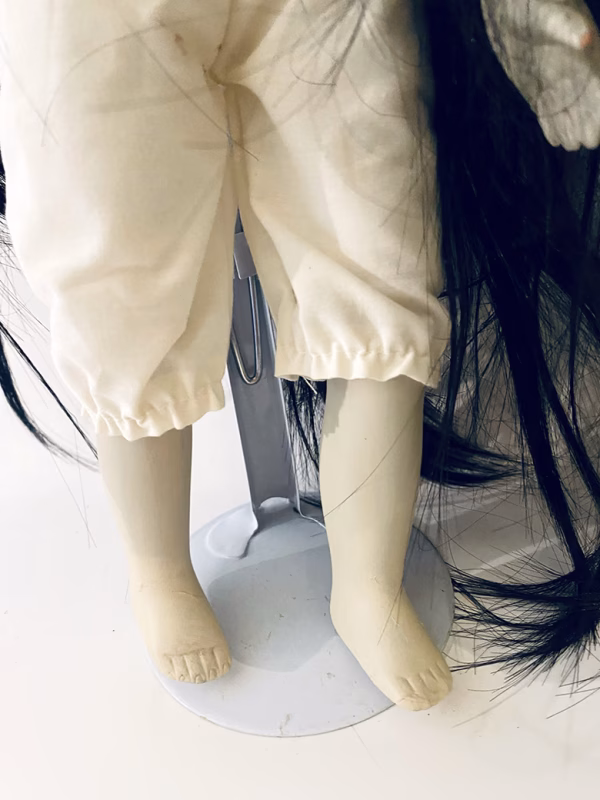 Uncanny girl doll with long dark brown hair. Legs and feet.