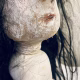 Uncanny girl doll with long dark brown hair. Face profile view close-up mouth.
