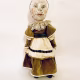 A doll wearing a sage green velvet and cream cotton dress. With a kilner jar clip over its head.