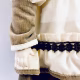 A doll wearing a sage green velvet and cream cotton dress. Close-up on right arm with hand an pink nails.