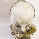 A doll wearing a sage green velvet and cream cotton dress. With a kilner jar clip over its head.