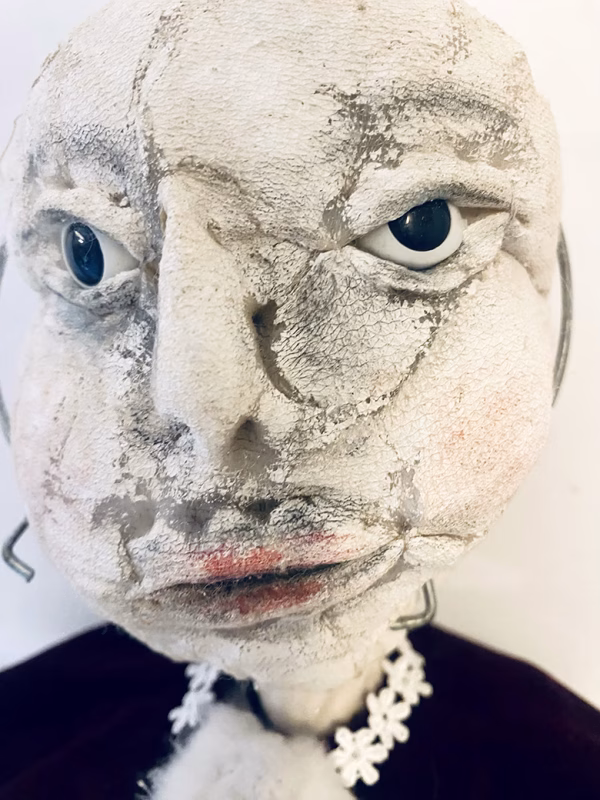 Hacked doll with a Kilner jar clip around its 'ugly' uncanny head.