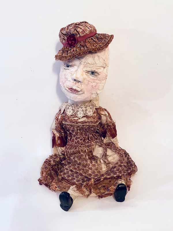 Hacked doll with decayed silk dress. The original ‘pretty’ head is replaced with an oversized, bald, uncanny head.