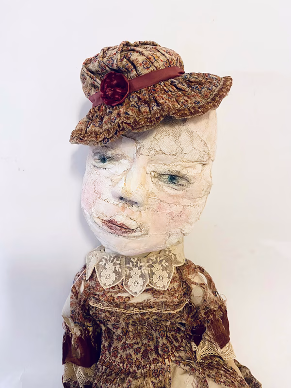 Hacked doll with decayed silk dress. The original ‘pretty’ head is replaced with an oversized, bald, uncanny head.