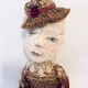 Hacked doll with decayed silk dress. The original ‘pretty’ head is replaced with an oversized, bald, uncanny head.