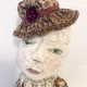 Hacked doll with decayed silk dress. The original ‘pretty’ head is replaced with an oversized, bald, uncanny head.