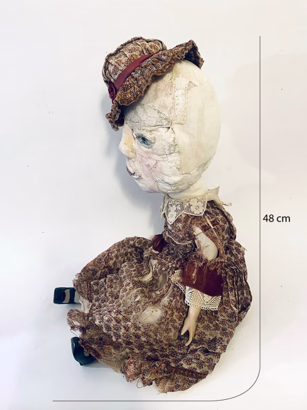 Hacked doll with decayed silk dress. The original ‘pretty’ head is replaced with an oversized, bald, uncanny head.