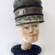 Head sculpture resting on a household iron trivet with a head piece of three stacked laboratory sieves.
