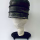 Head sculpture resting on a household iron trivet with a head piece of three stacked laboratory sieves.