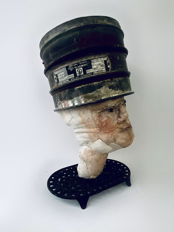Head sculpture resting on a household iron trivet with a head piece of three stacked laboratory sieves.