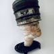 Head sculpture resting on a household iron trivet with a head piece of three stacked laboratory sieves.
