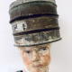 Head sculpture resting on a household iron trivet with a head piece of three stacked laboratory sieves.