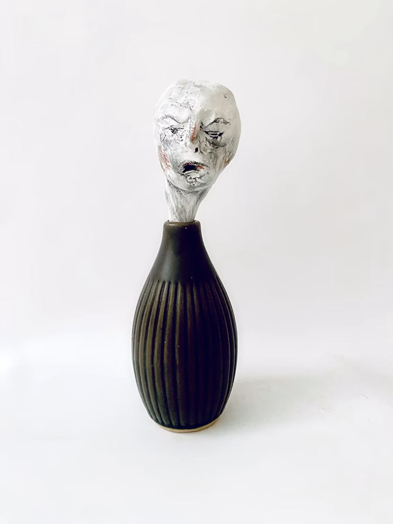 Small sculpture head emerging from ceramic pot
