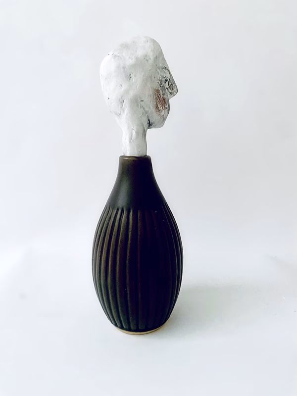 Small sculpture head emerging from ceramic pot