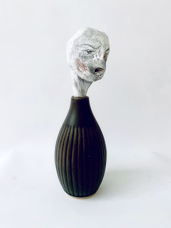 Small sculpture head emerging from ceramic pot