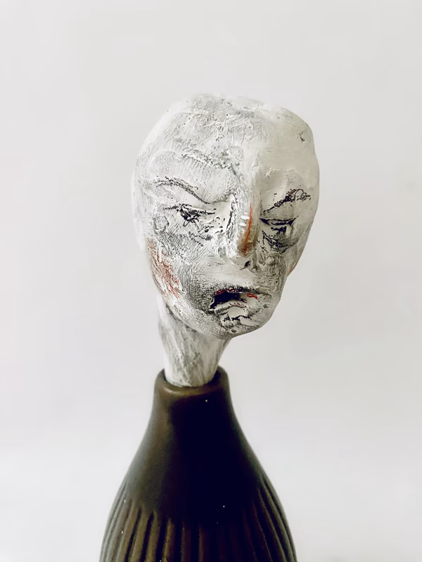 Small sculpture head emerging from ceramic pot