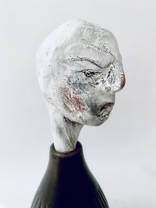 Small sculpture head emerging from ceramic pot