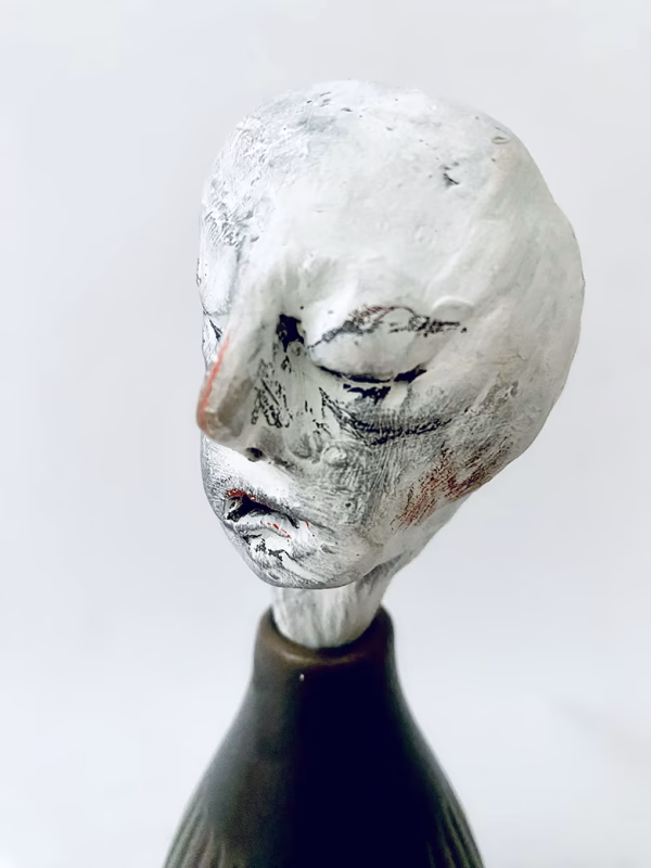 Small sculpture head emerging from ceramic pot