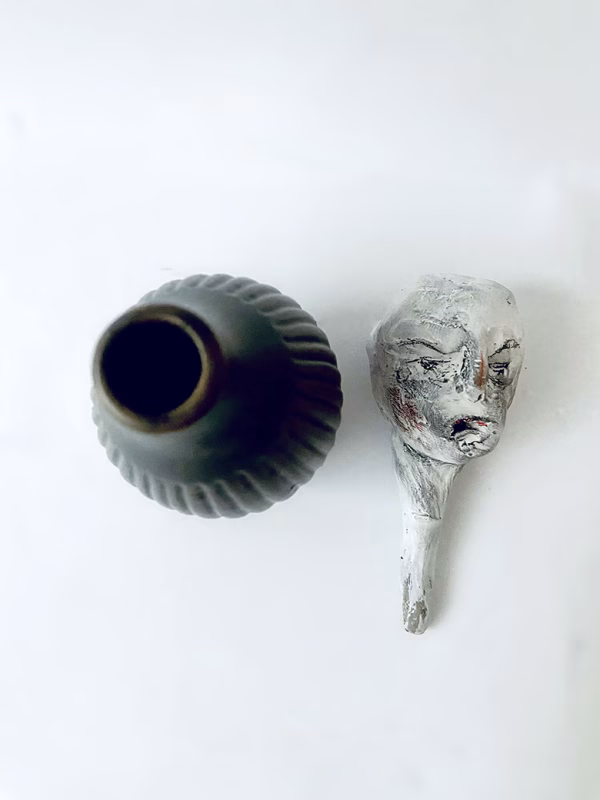 Small sculpture head next to ceramic pot