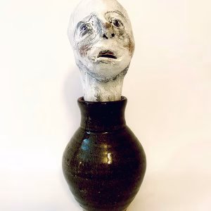 Small sculpture head emerging from ceramic pot