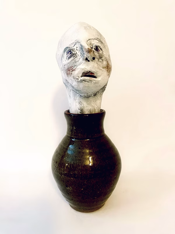 Small sculpture head emerging from ceramic pot