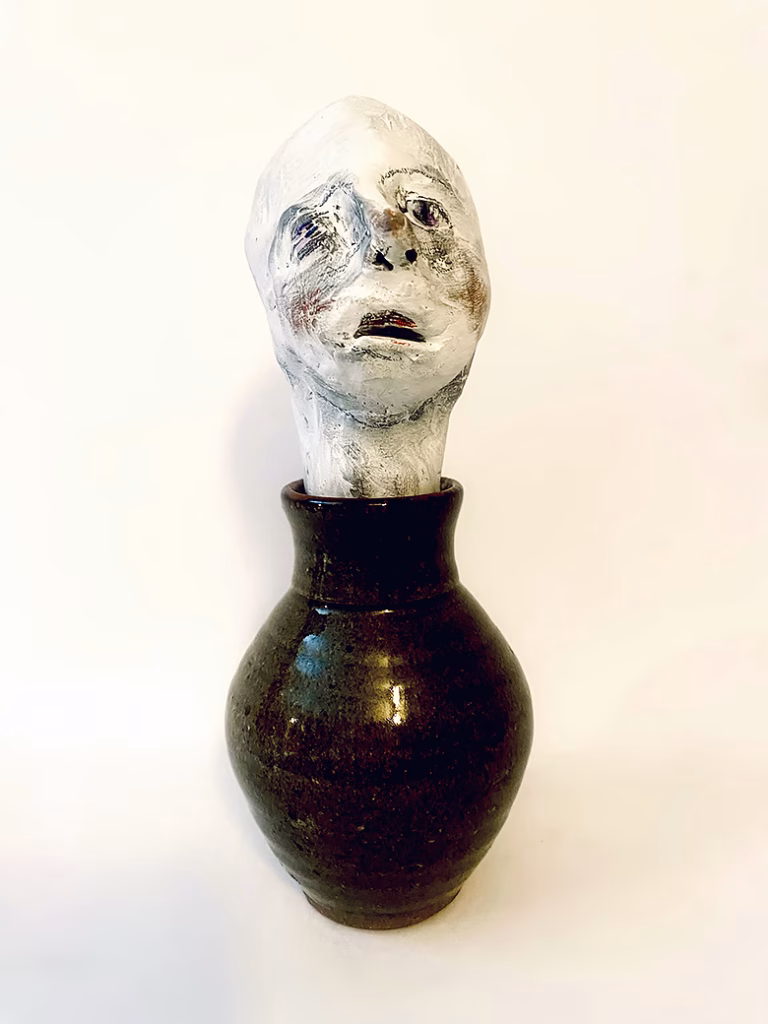 Small sculpture head emerging from ceramic pot