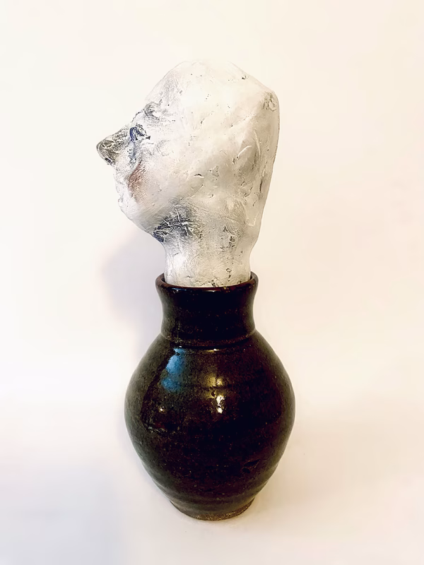 Small sculpture head emerging from ceramic pot