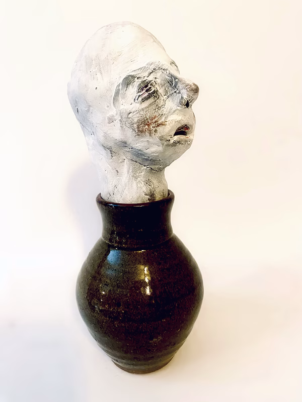 Small sculpture head emerging from ceramic pot