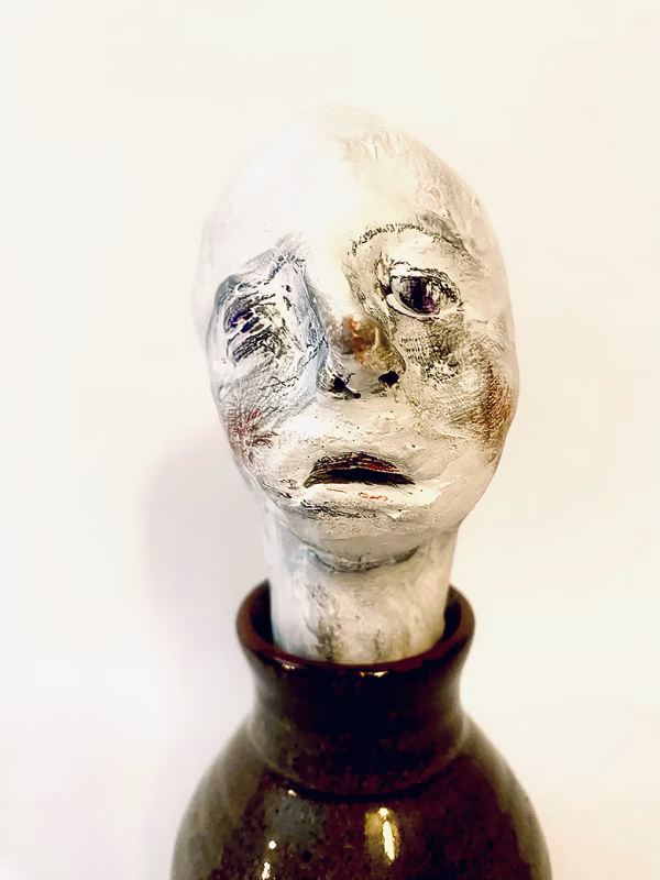 Small sculpture head emerging from ceramic pot