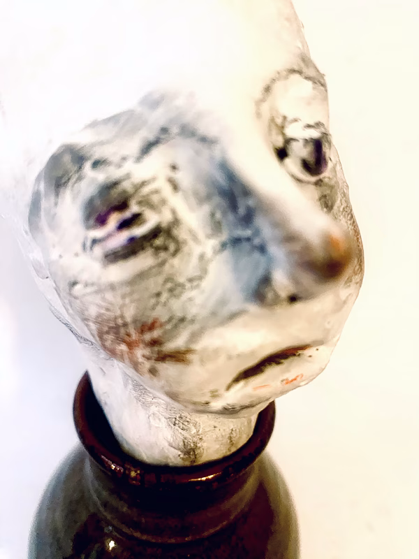 Small sculpture head emerging from ceramic pot