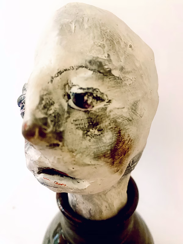 Small sculpture head emerging from ceramic pot