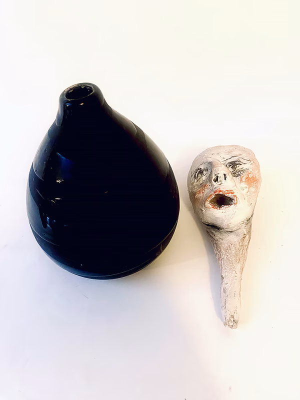 Small sculpture head next to ceramic pot