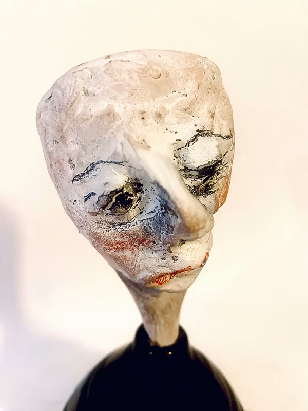 Small sculpture head emerging from ceramic pot (close-up)