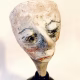 Small sculpture head emerging from ceramic pot (close-up)