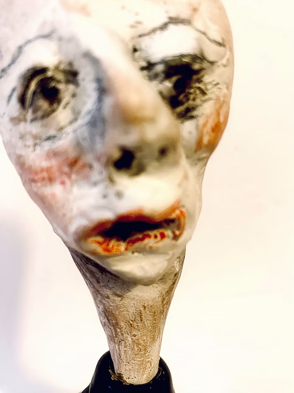 Small sculpture head emerging from ceramic pot (close-up)