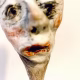 Small sculpture head emerging from ceramic pot (close-up)